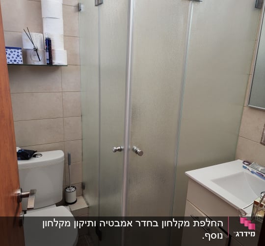 מקלחון זכוכית עם דלתות מתכת בחדר אמבטיה